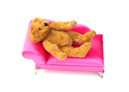 Teddy bear resting on a pink couch, illustrating the personal choice of disclosing an autism diagnosis